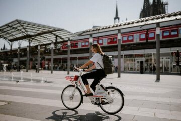 Eine Frau mit Call a Bike Fahrrad vor dem Kölner Hauptbahnhof (Breslauer Platz)